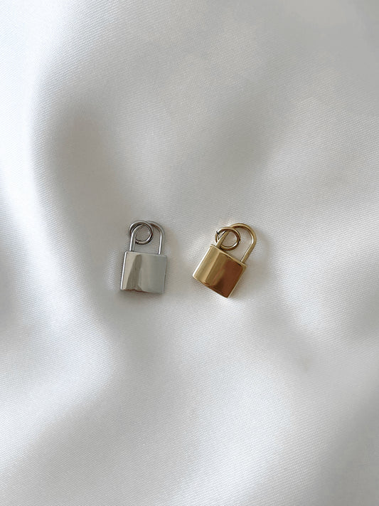 Unser schlichter Charm Anhänger ''Lock'' in Form eines Schlosses ist die perfekte Wahl, um deinem Schmuck eine persönliche Note zu verleihen.  Gefertigt aus hochwertigem Edelstahl und mit 18k Gold vergoldet, ist dieser Anhänger wasserfest und nickelfrei.  Er kann an all unsere Armbänder oder Ketten angebracht werden und verleiht deinem Schmuckstein eine stilvolle und individuelle Ausstrahlung.