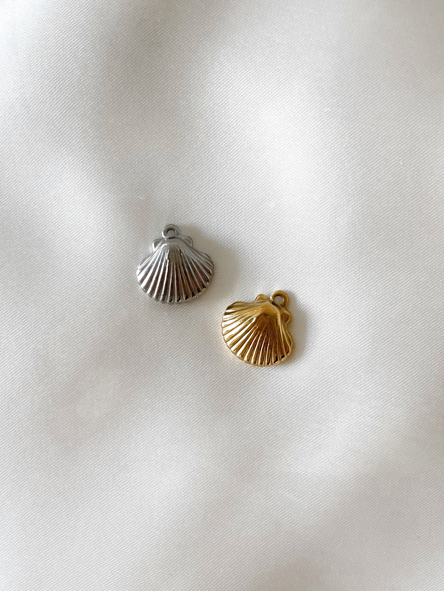 Unser Charm Anhänger ''Sand Shell'' bringt eine maritime Eleganz in dein Schmuckstück.  Hergestellt aus hochwertigem Edelstahl und mit 18k Gold vergoldet, ist dieser Anhänger wasserfest und nickelfrei.  Er lässt sich leicht an all unsere Armbänder oder Ketten anbringen und verleiht deinem Schmuck eine stilvolle Note, die ans Meer erinnert.